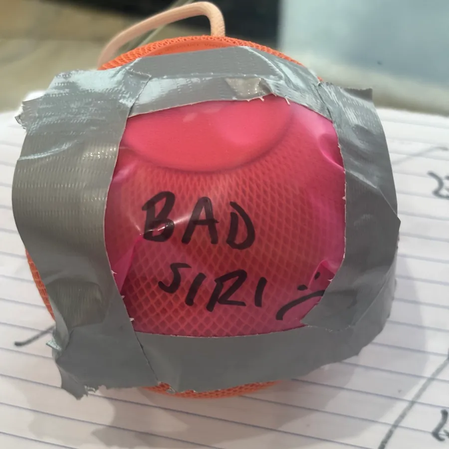 An orange HomePod mini with duct tape across the front and BAD SIRI written on it in marker